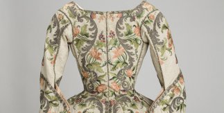 Vista trasera de una casa femenina, s. XVIII, seda labrada, con aplicación de bordado que dibuja motivos florales polícromos.